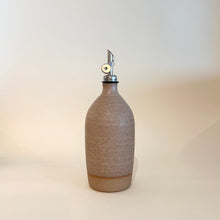 Speckled ceramic bottle with a metallic cap on a light background